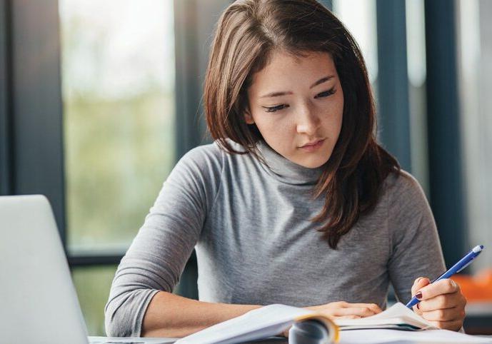 年轻女子在日记中记笔记的镜头. 女大学生在图书馆准备考试笔记.